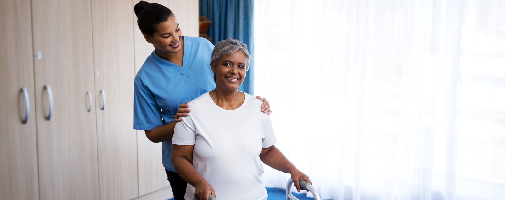 caregiver in a uniform and an elder standing